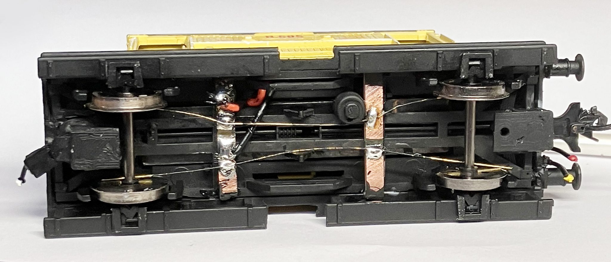 Electrical pickups contact the backs of the wheel flanges to carry DCC current to the the stay-alive inputs (red and black wires visible in this shot). The stay-alive unit's bridge rectifier then converts that DCC flat waveform signal to DC current.